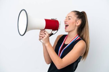 Young caucasian woman with medals isolated on white background shouting through a megaphone