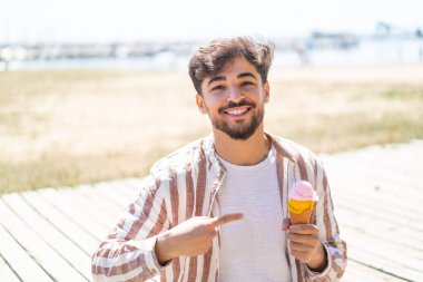 Açık havada elinde kornet dondurması olan yakışıklı bir Arap.