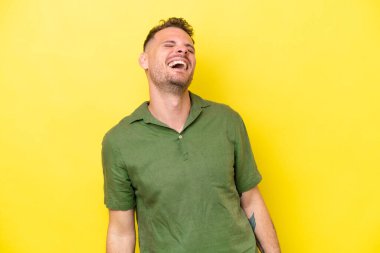 Sarı arka planda izole edilmiş genç beyaz yakışıklı adam gülüyor.
