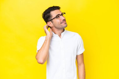 Izole sarı arka plan üzerinde genç yakışıklı adam bir fikir düşünme