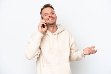 Beyaz arka planda izole edilmiş beyaz tenli yakışıklı bir adam cep telefonuyla sohbet ediyor.