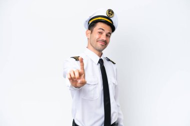 İzole edilmiş beyaz arka plan üzerinde uçak pilotu parmağını kaldırıyor ve gösteriyor.