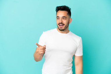 Kafkasyalı genç adam mavi arka planda izole edilmiş bir şekilde parmağını kaldırarak çözümü anlamaya çalışıyor.