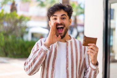 Elinde cüzdanı olan yakışıklı bir Arap, ağzı açık bağırıyor.