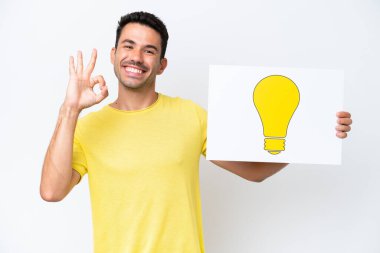 İzole edilmiş beyaz arka planda genç yakışıklı bir adam elinde üzerinde ok işareti olan bir afiş tutuyor.