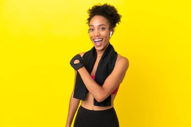 Sarı arka planda izole edilmiş genç Afrikalı spor kadını zaferi kutluyor.