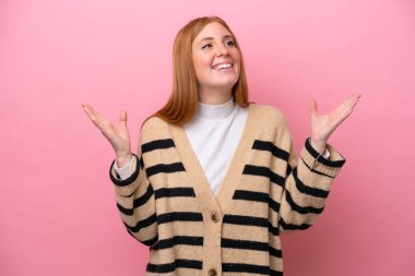 Genç kızıl saçlı kadın pembe arka planda izole edilmiş, gülümsüyor.