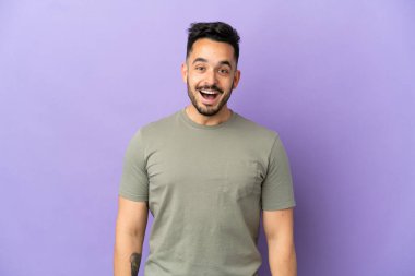 Mor arka planda yüzü sürpriz bir ifadeyle izole edilmiş genç beyaz bir adam.