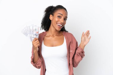 Genç Afrikalı Amerikalı bir kadın, beyaz arka planda izole edilmiş, mutlu bir ifadeyle selamlanan bir sürü para alıyor.