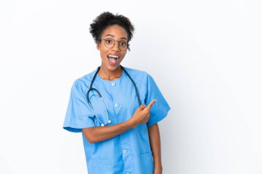 Genç cerrah Afrikalı Amerikalı kadın. Beyaz arka planda izole edilmiş. Şaşırmış ve işaret ediyor.