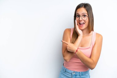 Beyaz arka planda izole edilmiş genç beyaz bir kadın bir ürünü sunmak ve bir şeyler fısıldamak için kenarı işaret ediyor.