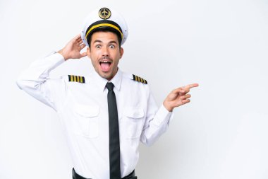 İzole edilmiş beyaz arka plan üzerinde uçak pilotu şaşırdı ve parmağını yana çevirdi.