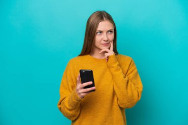 Genç Rus kadın mavi arka planda cep telefonu kullanarak izole edildi.