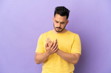 Mor arka planda izole edilmiş beyaz bir adam ellerinde acıdan muzdarip.