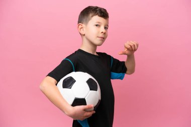 Küçük beyaz futbolcu çocuk pembe arka planda soyutlanmış gururlu ve kendini beğenmiş.