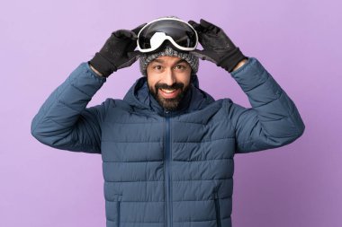 İzole edilmiş mor arka planda snowboard gözlüklü kayakçı.