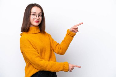 Beyaz arka planda izole edilmiş genç Ukraynalı bir kadın parmak göstererek bir ürün sunuyor.