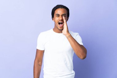 Örgülü genç Afrikalı Amerikalı adam mor arka planda izole edilmiş ağzı açık bağırıyor.