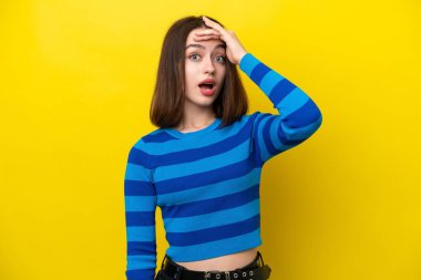Young Ukrainian woman isolated on yellow background doing surprise gesture while looking to the side