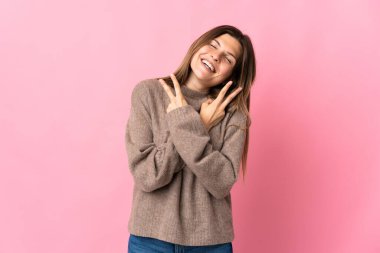 Genç Slovak kadın pembe arka planda izole edilmiş gülümsüyor ve zafer işareti gösteriyor.