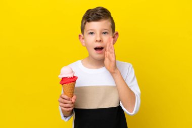 Sarı arka planda izole edilmiş kornet dondurması olan beyaz bir çocuk ağzı açık bağırıyor.