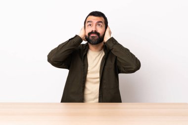 Masada sakallı beyaz bir adam hayal kırıklığına uğramış ve kulaklarını kapatmış..