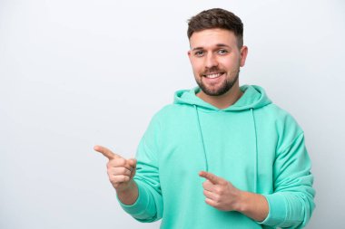 Beyaz arka planda izole edilmiş genç beyaz adam korkmuş ve kenarı işaret ediyor.