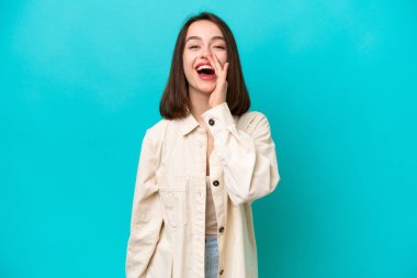 Mavi arka planda izole edilmiş genç Ukraynalı kadın ağzı açık bağırıyor.