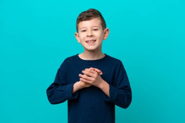 Küçük çocuk mavi arka planda yalnız gülüyor.