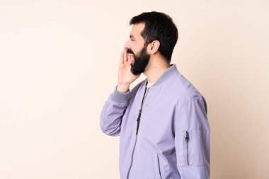 Sakallı beyaz bir adam izole edilmiş arka planda ceket giyiyor ve ağzı sonuna kadar açık bağırıyor.