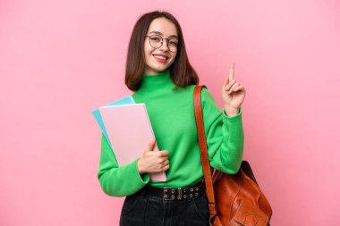 Genç Ukraynalı bir kadın pembe arka planda izole edilmiş ve en iyinin işareti olarak parmağını kaldırıyor.