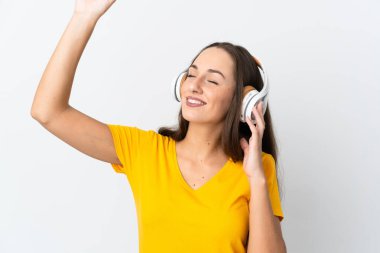 Genç İspanyol kadın soyutlanmış beyaz arka planda müzik ve dans dinliyor.