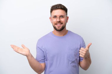 Beyaz arka planda izole edilmiş genç beyaz bir adam, bir ilan vermek ve onaylamak için avucunda hayali bir kopyalama alanı tutuyor.