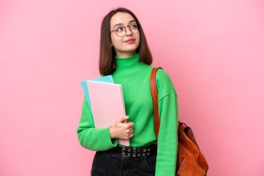 Genç öğrenci Ukraynalı kadın pembe arka planda izole edilmiş, yukarı bakarken bir fikir düşünüyor.