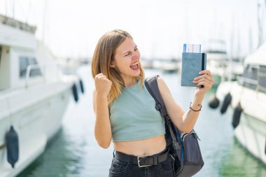 Dışarıda elinde pasaportu olan genç sarışın bir kadın zaferi kutluyor.