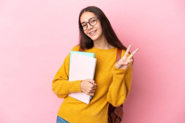 Tecrit edilmiş genç bayan öğrenci gülümsüyor ve zafer işareti gösteriyor.