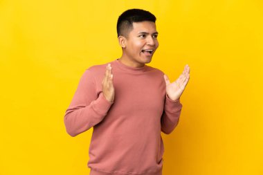 Genç Ekvadorlu adam, sarı arka planda yalıtılmış ve şaşırmış bir yüz ifadesi var.