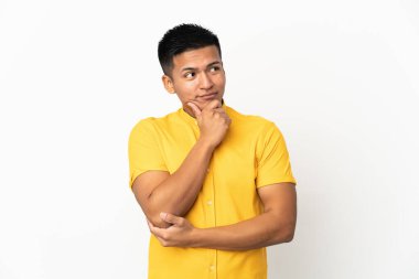 Genç Ekvadorlu bir adam beyaz arka planda izole edilmiş, yukarı bakarken bir fikir düşünüyor.