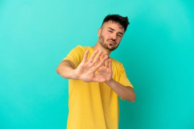 Kafkasyalı genç adam mavi arka planda izole edilmiş gergin eller öne doğru uzanıyor.