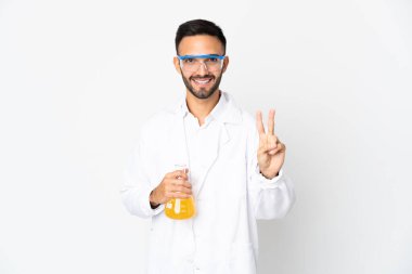 Beyaz arka planda izole edilmiş genç bilim adamı gülümsüyor ve zafer işareti gösteriyor.