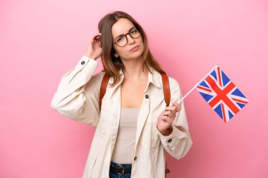 Kafkasyalı genç bir kadın pembe arka planda izole edilmiş bir Birleşik Krallık bayrağı tutuyor.