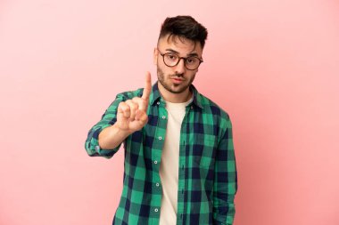 Pembe arka planda izole edilmiş beyaz bir adam ciddi bir ifadeye sahip birini sayıyor.