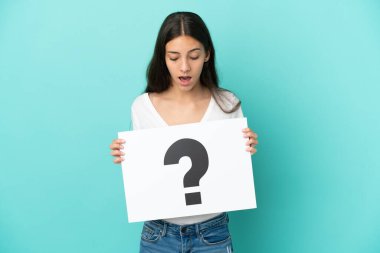 Mavi arka planda izole edilmiş genç bir Fransız kadın soru işareti sembollü bir pankart tutuyor.