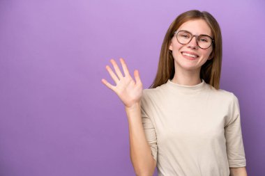 Mor arka planda izole edilmiş genç İngiliz kadın mutlu bir ifadeyle selamlıyor.