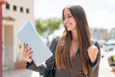 Dışarıda genç bir bayan öğrenci zaferi kutluyor.