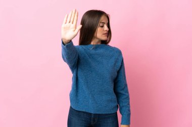 Genç Uruguaylı kadın pembe arka planda izole edilmiş. Durma hareketi yapıyor ve hayal kırıklığına uğruyor.