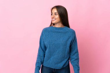 Genç Uruguaylı kadın pembe arka planda izole edilmiş, yana bakıyor ve gülümsüyor.