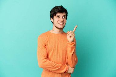 Genç Rus adam mavi arka planda izole edildi. Harika bir fikre işaret ediyor.