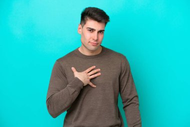 Mavi arka planda izole edilmiş genç beyaz adam kendini işaret ediyor.