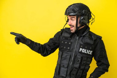 Özel Tim 'in beyaz adamı sarı arka planda izole edildi. Parmağını yana uzattı ve bir ürün sundu.